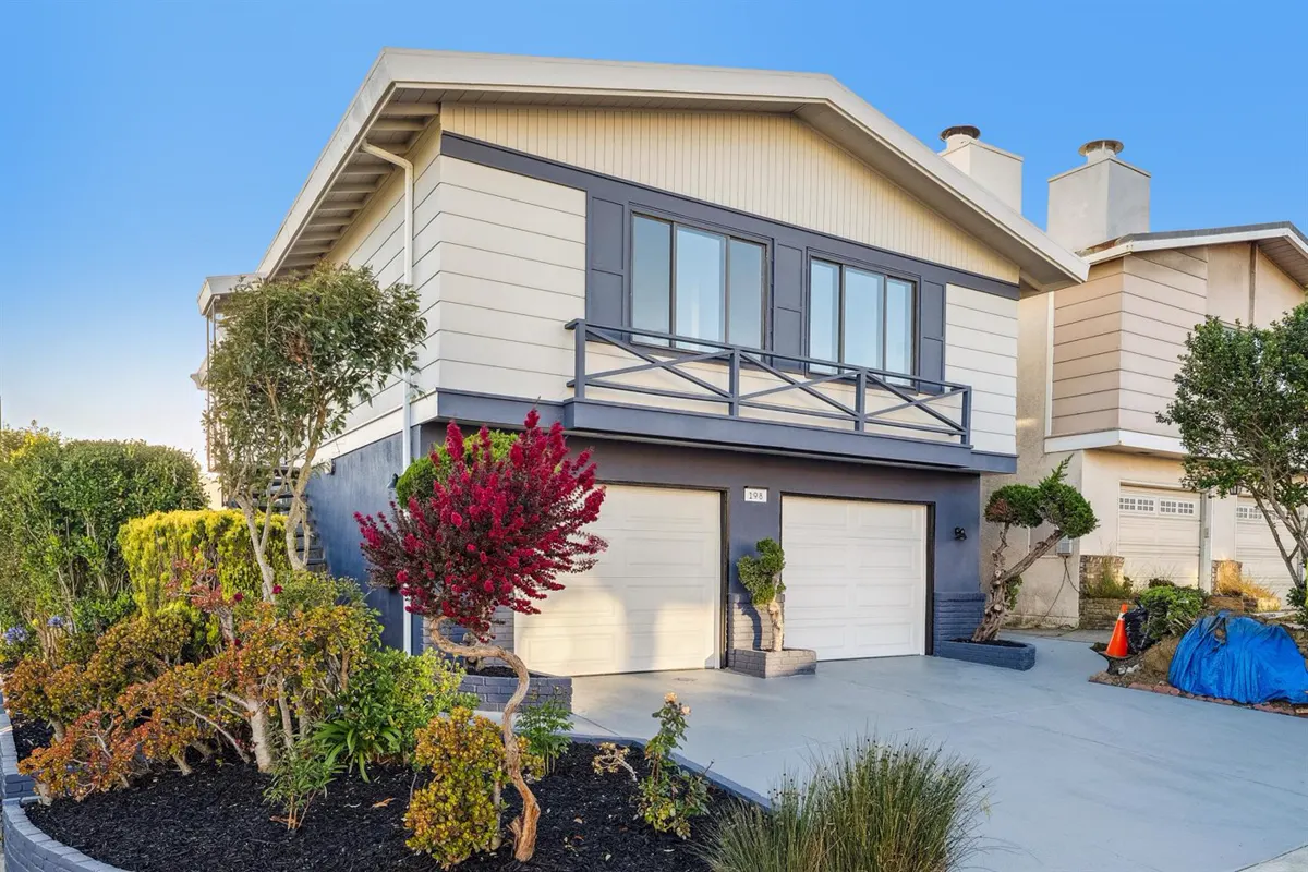 Rebuilt corner home with new siding, a balcony railing and a landscaped planter wall