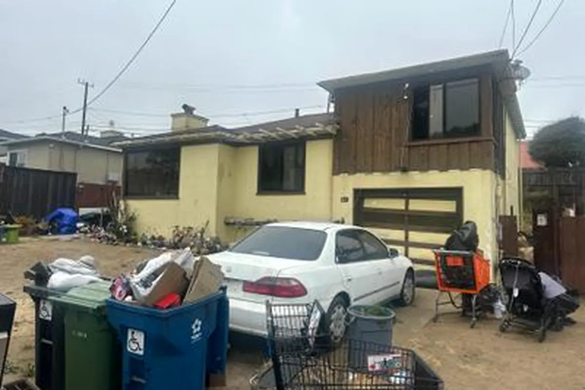The house before the rebuild: fire-damaged, with a debris-filled driveway
